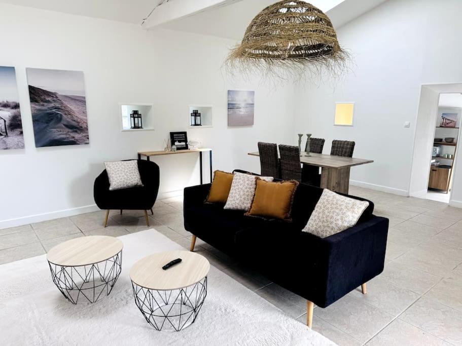 - un salon avec un canapé noir et deux chaises dans l'établissement Charmante maison aux Sables, à Les Sables-dʼOlonne