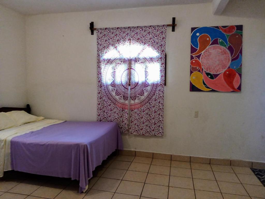 a bedroom with a bed and a painting on the wall at ESPERANZA Casa de Huéspedes in Puerto Escondido