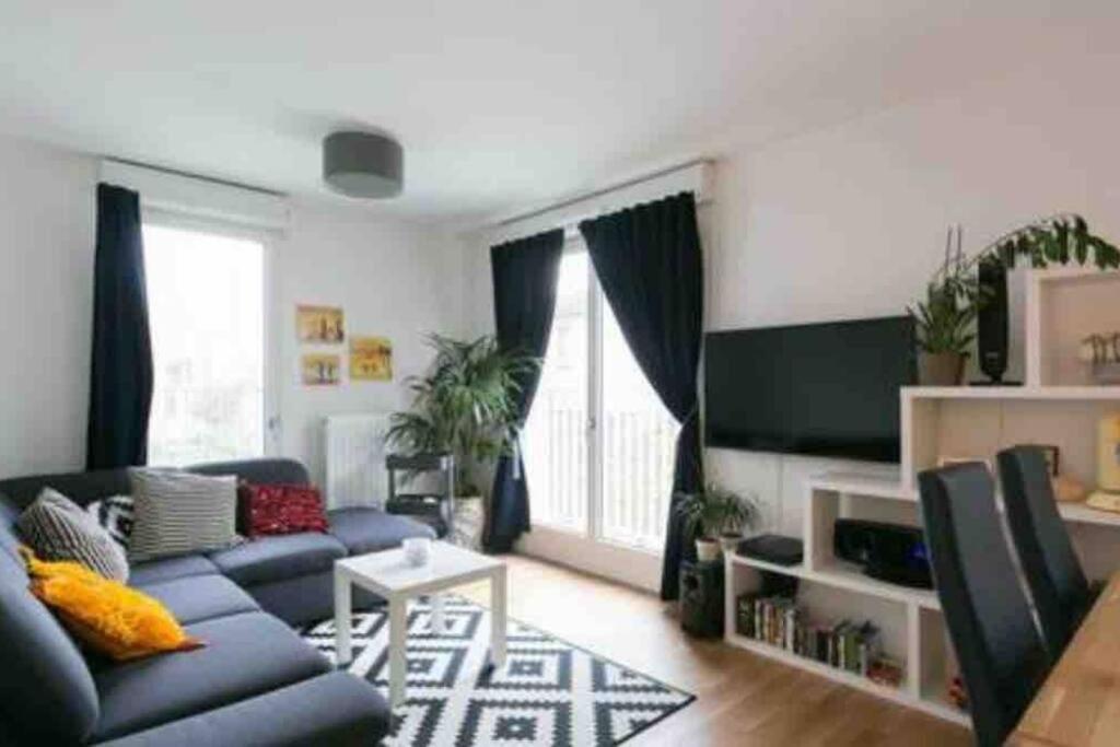 a living room with a blue couch and a tv at Cozy & Quiet Getaway Just 300m from Paris with Free Private Parking in Gentilly