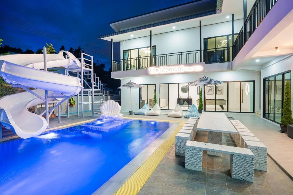 a house with a swimming pool with a slide at The Moment Pool Villa Bangsaray in Bang Sare