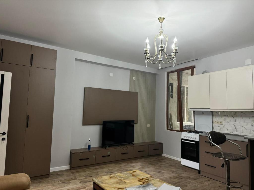 a living room with a television and a chandelier at House in the Bamboos in Batumi
