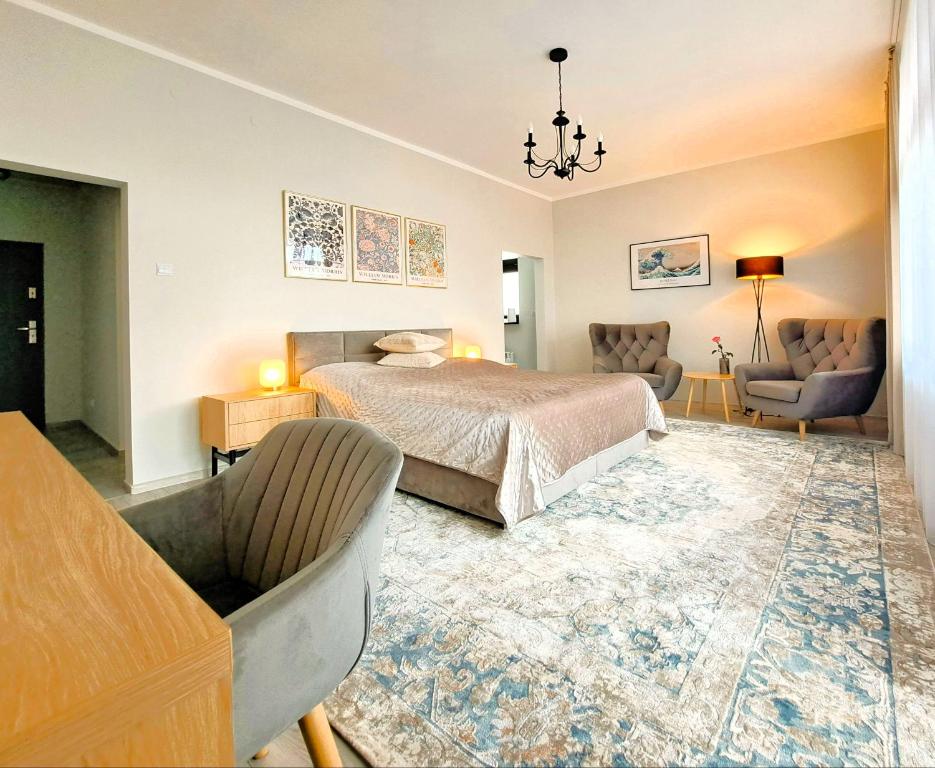 a bedroom with a bed and a couch and chairs at Tullu Apartament - w centrum, blisko bulwaru, blisko molo in Ostróda