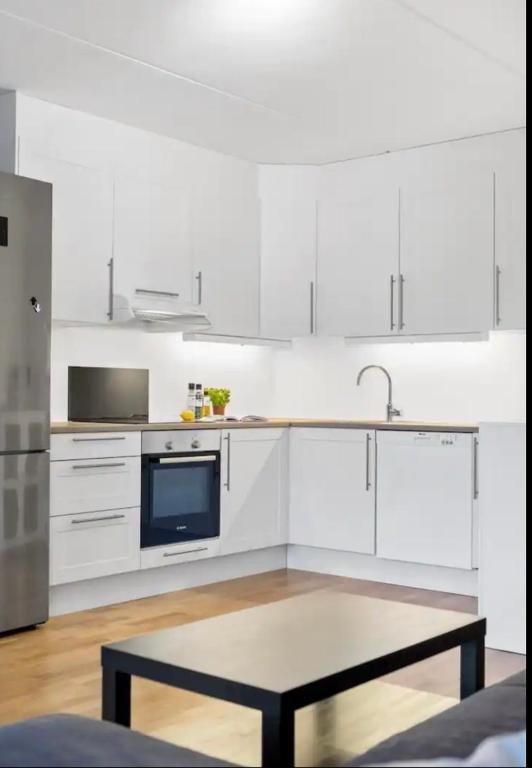 a white kitchen with white cabinets and a table at Sentral leilighet til utleie in Stavanger