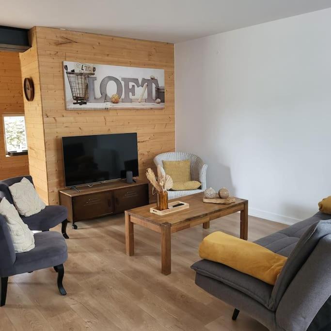 un salon avec une télévision, une table et des chaises dans l'établissement O Nid Naturel, à Mauléon