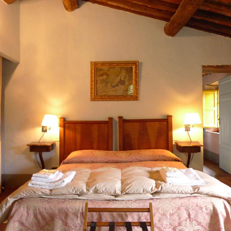 a bedroom with a bed with two chairs and a painting at Azienda Agricola Fabbrica Di San Martino in Lucca