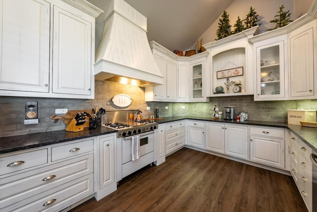 a white kitchen with white cabinets and wooden floors at The Great Escape Sunsets Hot Tub Bliss in Shaver Lake