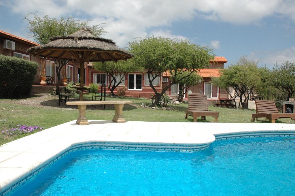 uma piscina com uma mesa de piquenique e um guarda-sol em Hosteria Amaneseres em Capilla del Monte