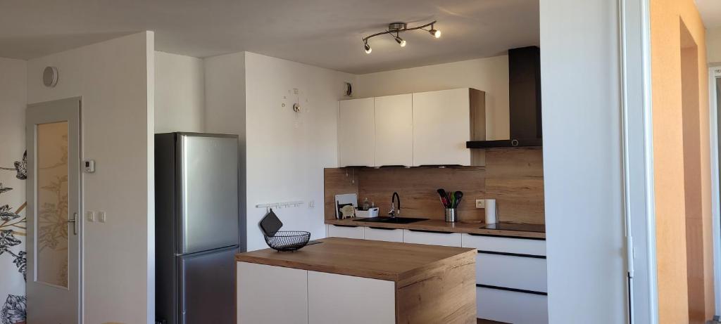 une cuisine avec des armoires blanches et un comptoir en bois dans l'établissement Cosy 51m2 proche gare pour Genève et tram 3 min, à Annemasse
