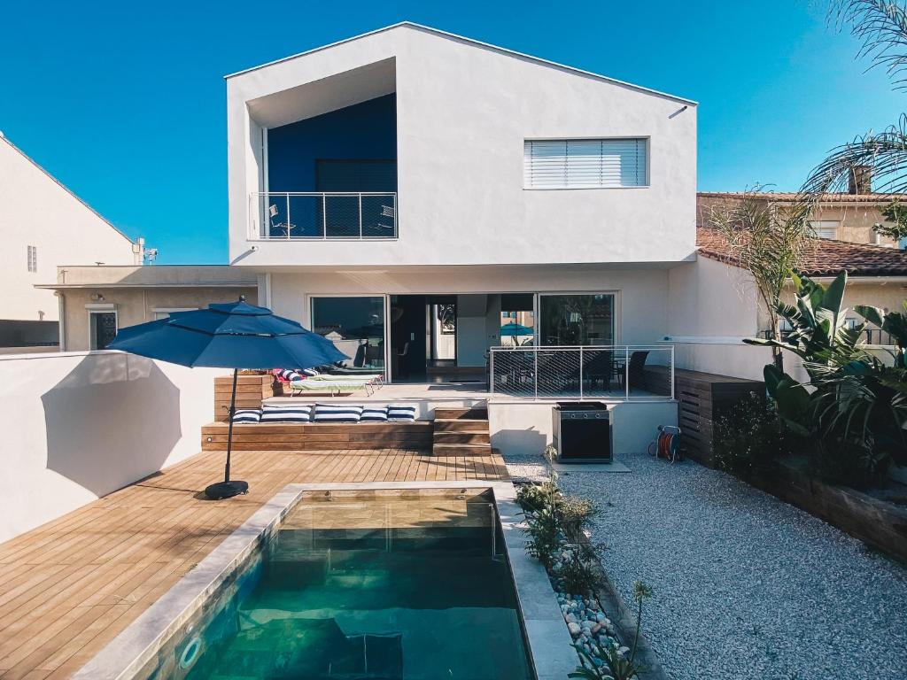 une maison avec une piscine et un parasol dans l'établissement Villa avec piscine à Carnon Plage à 20m de la plage idéale pour 8 à 10 personnes, à Mauguio