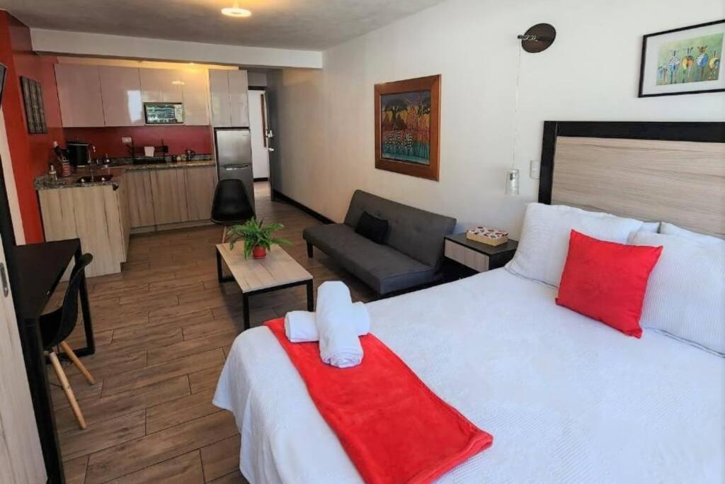 a bedroom with a large white bed with red pillows at DSt4 Well stocked studio in zone 15 in Guatemala