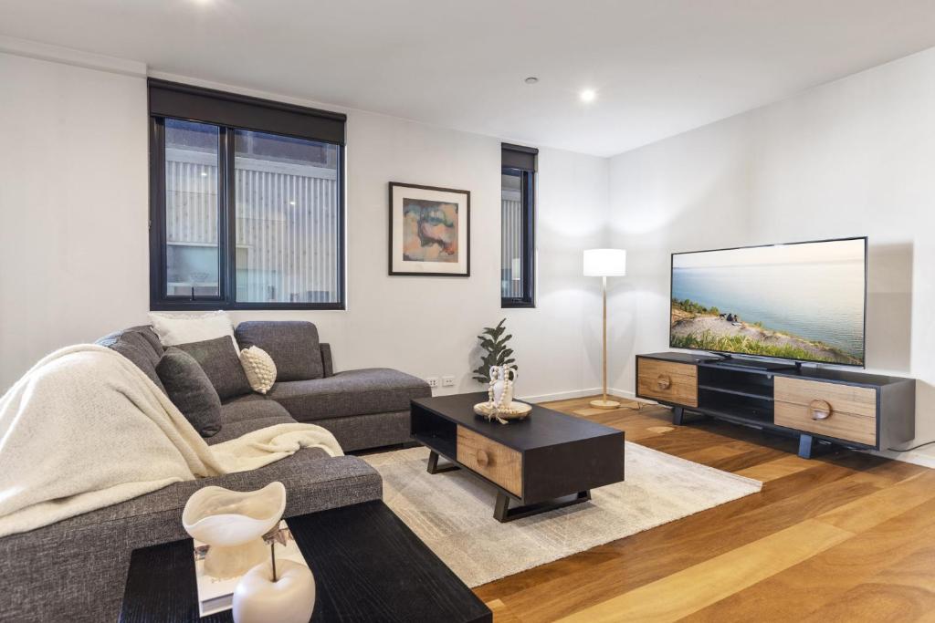 a living room with a couch and a flat screen tv at Oceanfront 2-Bed With Balcony & Study Nook in Geelong