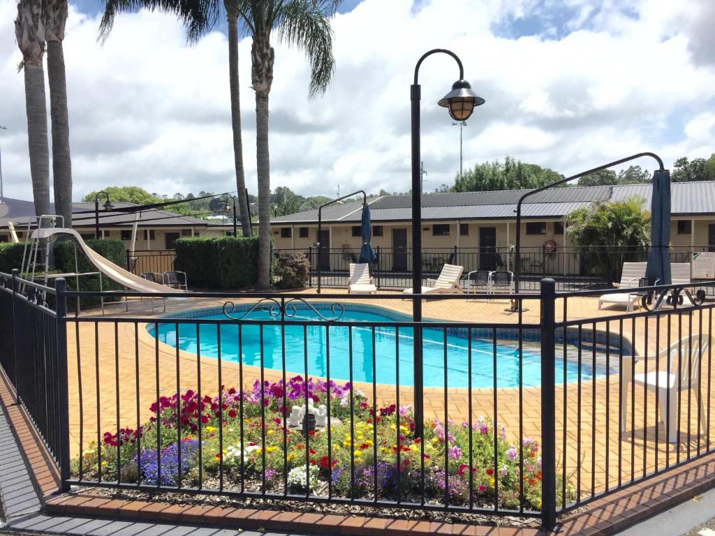 a pool at a resort with a slide and flowers at James Street Motor Inn in Toowoomba