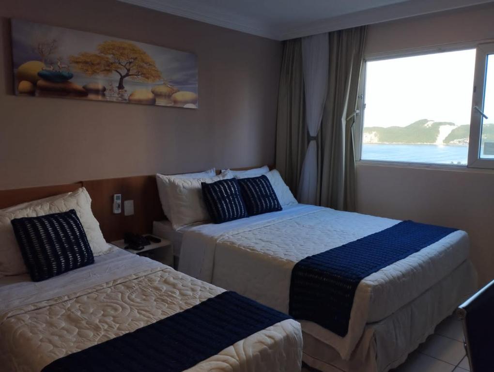 a hotel room with two beds and a window at PONTA NEGRA FLAT APART in Natal