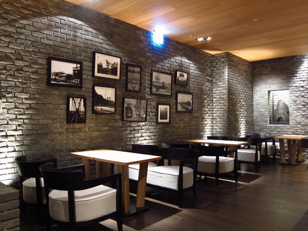 a restaurant with tables and chairs against a brick wall at Hotel Dùa in Kaohsiung