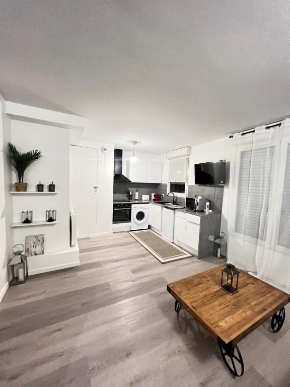 une cuisine avec des armoires blanches et une table en bois dans l'établissement Cosy home stade de France CDG airport, à Saint-Denis