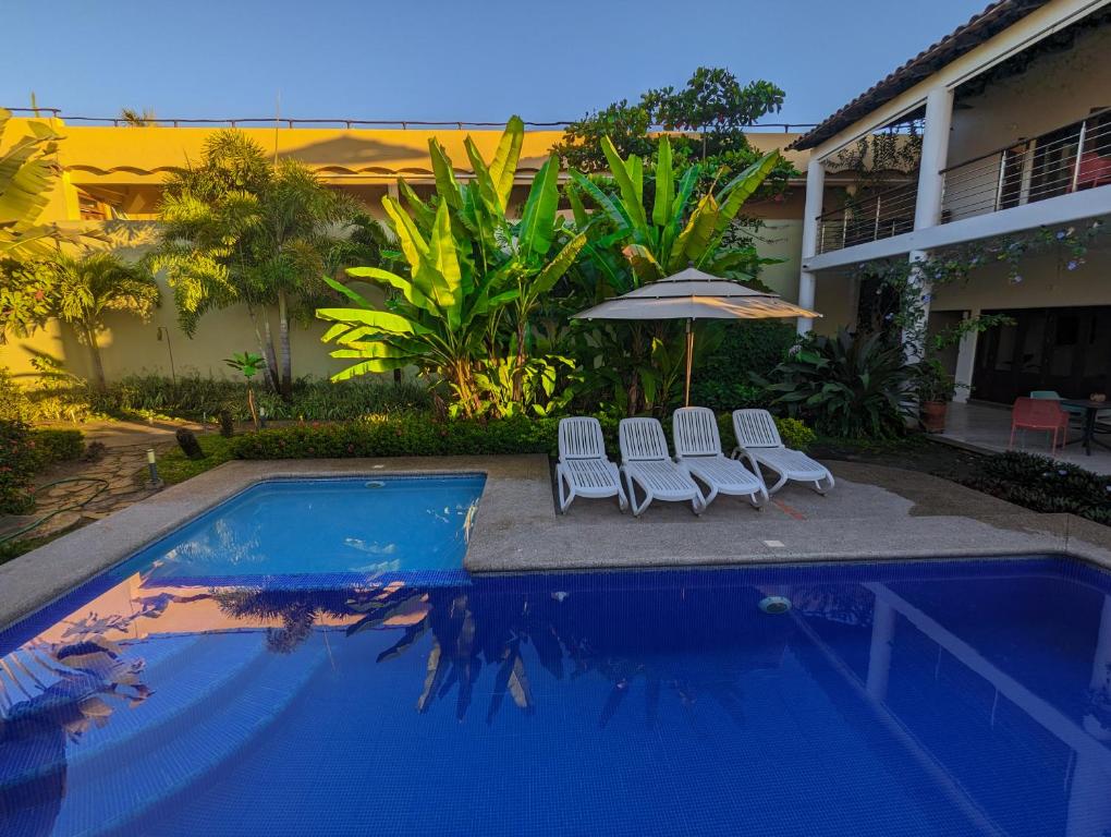 una piscina con 2 sillas y una sombrilla junto a una casa en Los Gallos - Suite, en Lo de Marcos