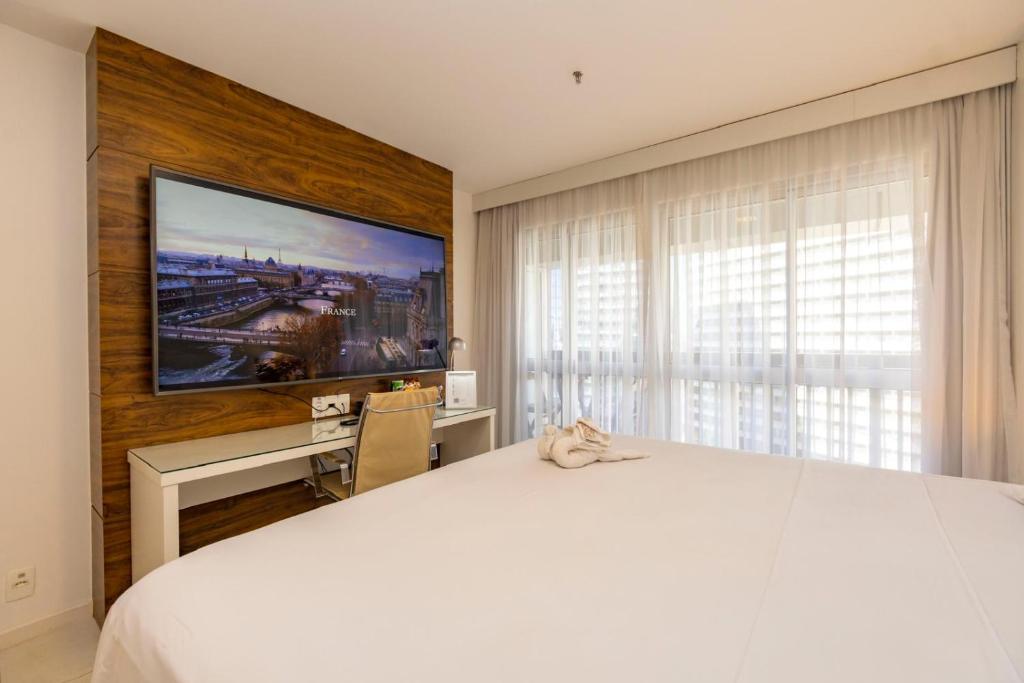 een slaapkamer met een groot wit bed en een bureau bij Charme de Paris Fusion in Brasilia