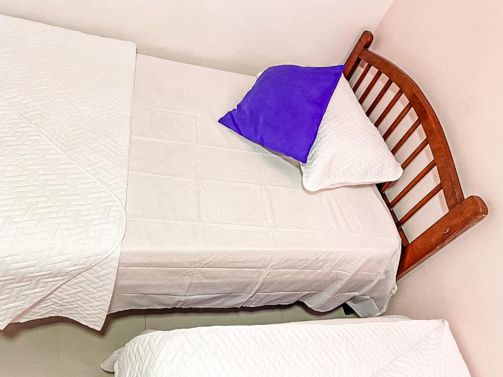 a bed with white sheets and a purple pillow at Apto cerca Estadio Metropolitano in Barranquilla