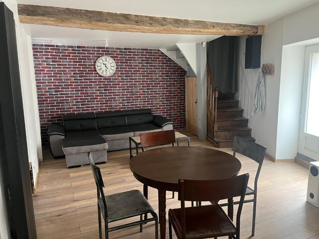 - un salon avec une table et un mur en briques dans l'établissement Petite maison de village, à Saint-Jean-sur-Mayenne