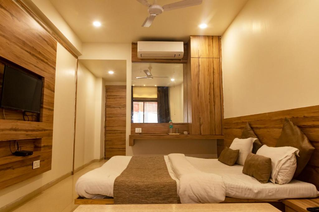 Una habitación de hotel con dos camas y un televisor. en Adarsh Palace Hotel, en Bhopal