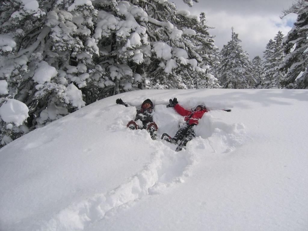 two people are laying in a pile of snow at Asahidake Yumoto Yukomanso in Higashikawa