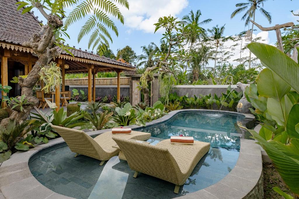 un patio trasero con piscina y sillas y una casa en Ratni Ubud Villa, en Ubud
