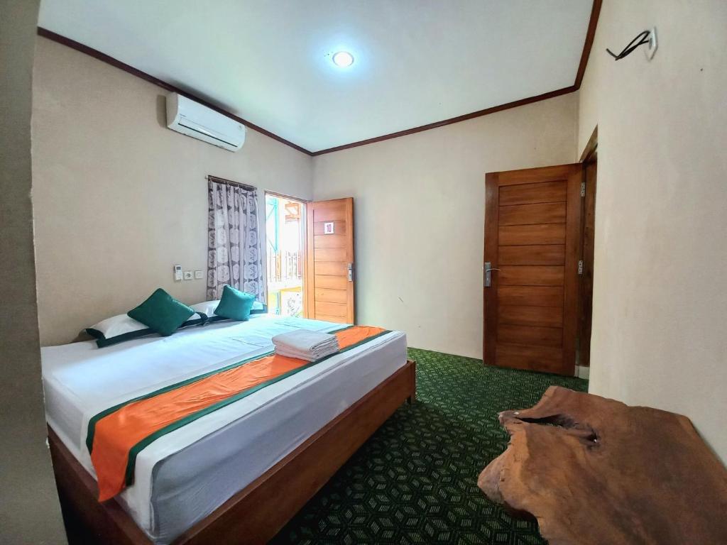 une chambre avec un grand lit et une porte en bois dans l'établissement Hotel Syariah Simply Homy dekat Yogyakarta International Airport, à Glagah