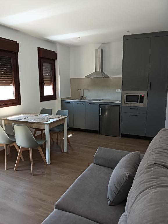 a living room with a couch and a table and a kitchen at Apartamentos Rural La Perla in Becilla de Valderaduey