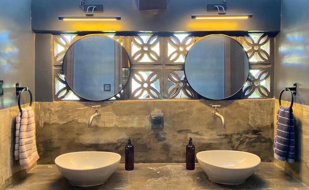 a bathroom with two sinks and two mirrors at Mojo Hostel in Puerto Princesa City
