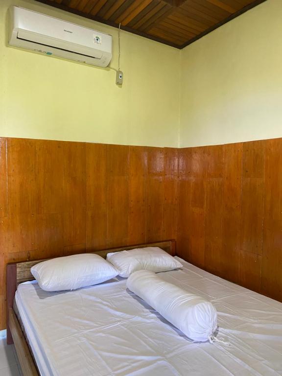 a bed with two pillows and a fan on the wall at Raja Ampat Family Guest House in Saonek