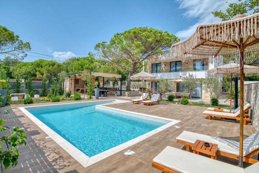 una piscina con sillas y sombrillas frente a una casa en VILLA Amfora, en Budva