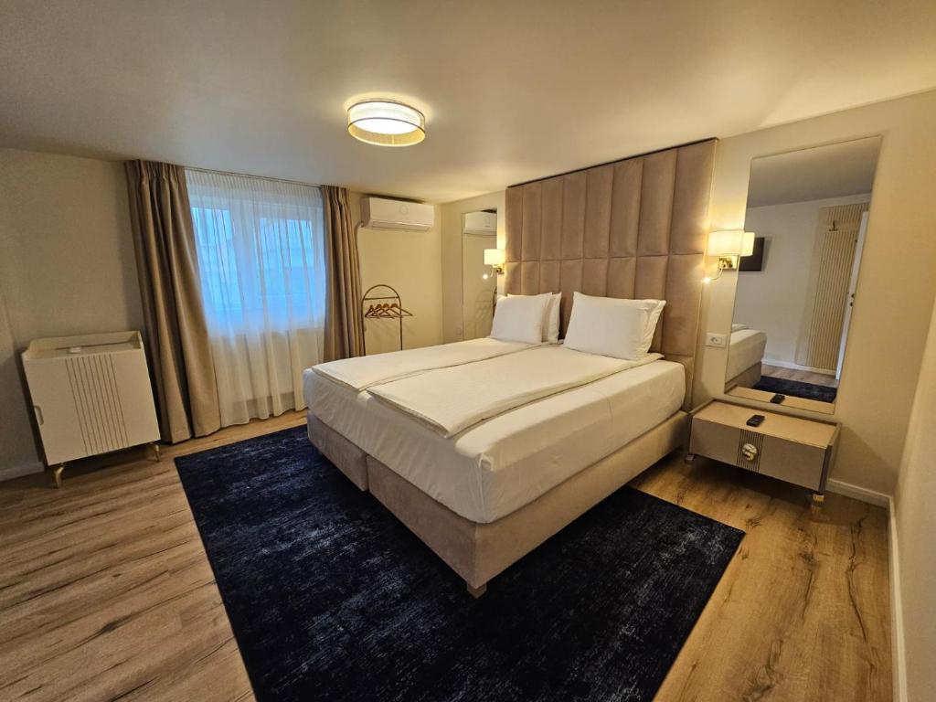 a bedroom with a large bed and a large window at Hotel Queen in Râmnicu Vâlcea