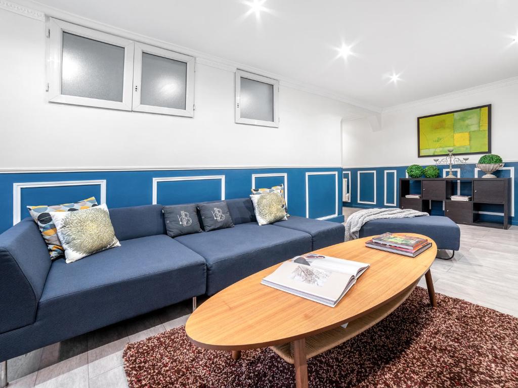 un salon avec un canapé bleu et une table dans l'établissement Manray House - Beautiful Three Bedroom Apartment- Paris Center, à Paris
