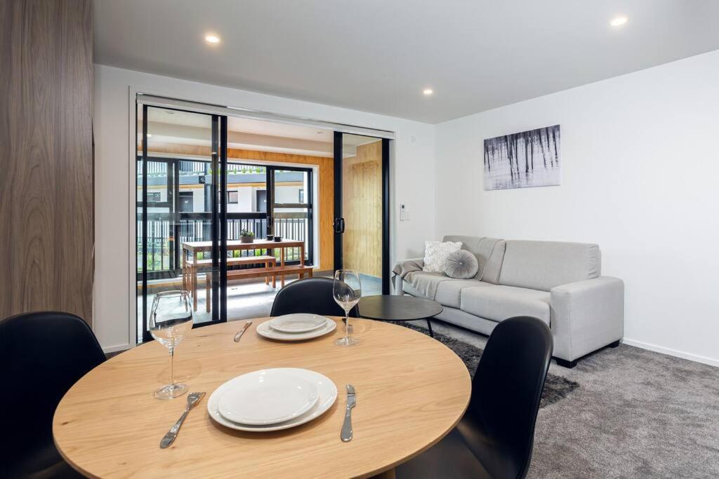 a living room with a wooden table and chairs at Stellar Central City Apartment - Hagley Park in Christchurch