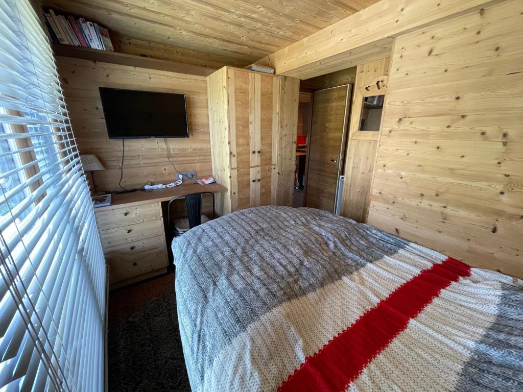 une chambre avec un lit dans une cabane en bois dans l'établissement Wintergarten, à Valmorel
