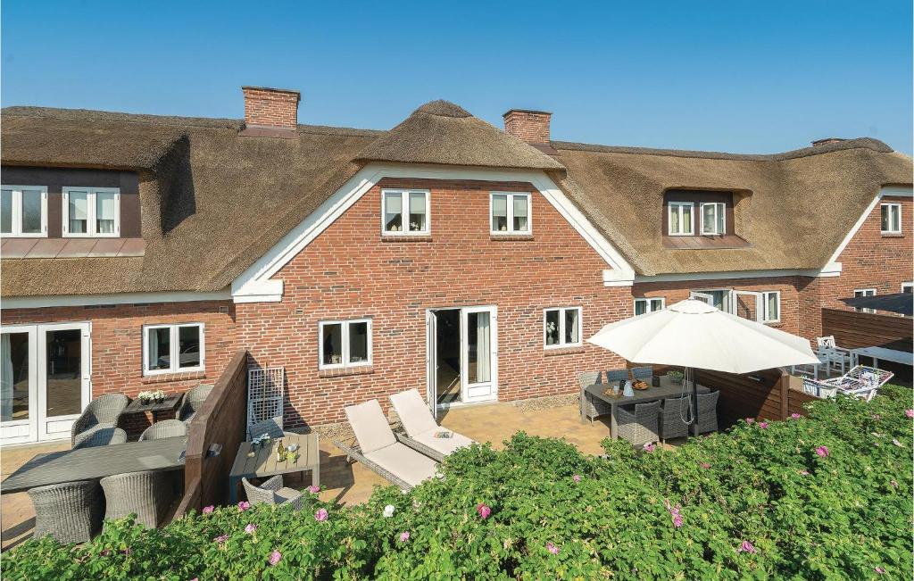 a large brick building with chairs and an umbrella at Holiday Home Horns Bjerge Vi in Blåvand