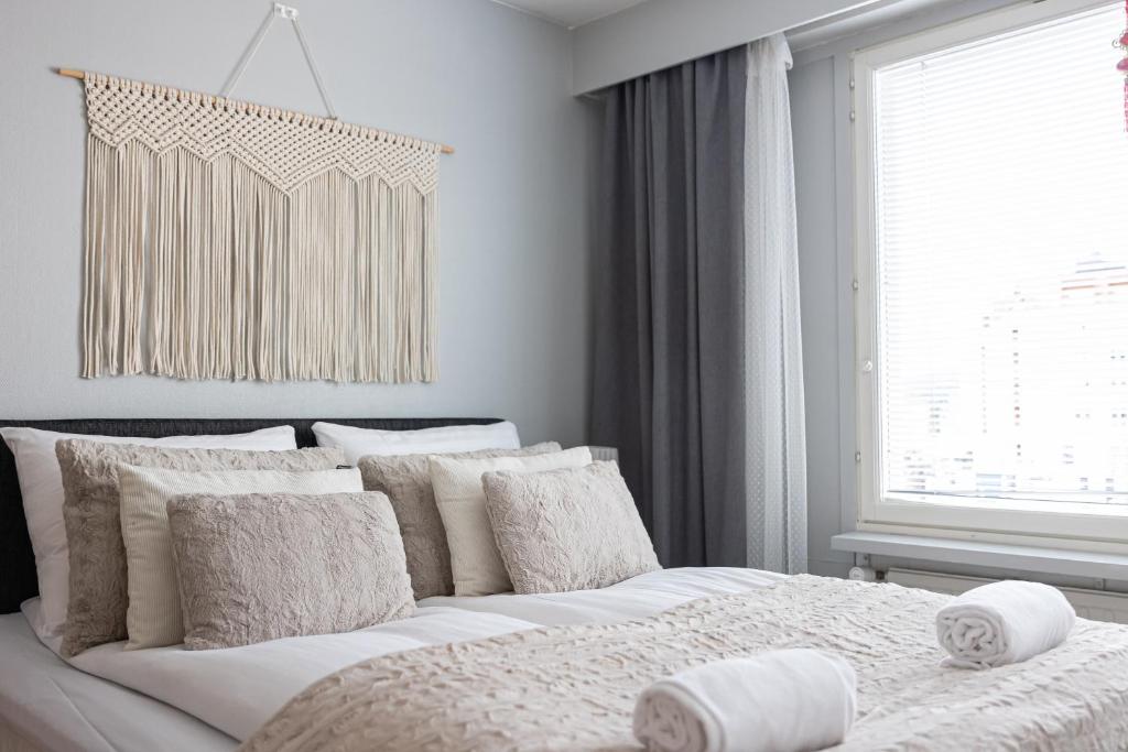 a bedroom with a white bed with pillows and a window at Cozy City Apartment By BookLapland in Rovaniemi