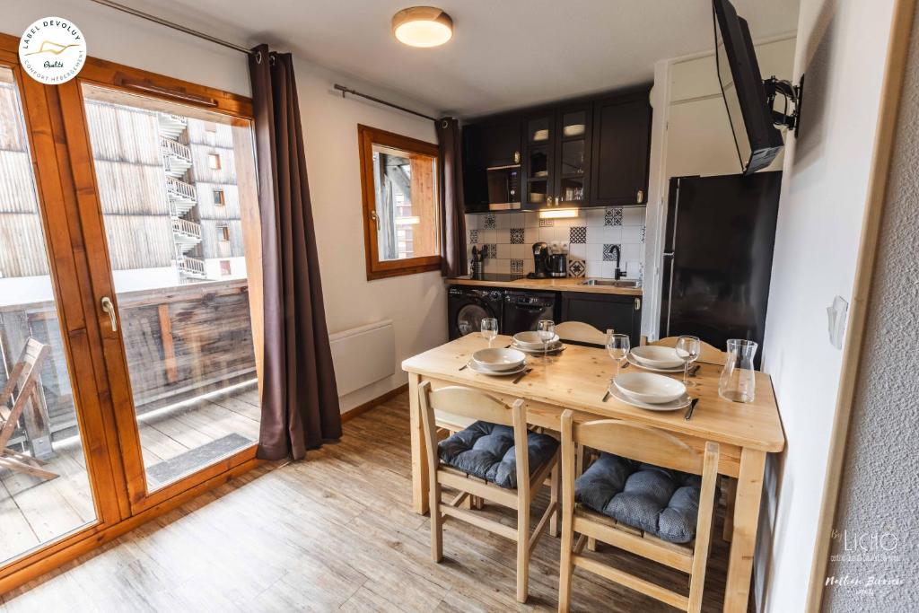 une cuisine avec une table en bois et une grande fenêtre dans l'établissement Appartement - Label Dévoluy 4 diamants, à Saint-Étienne-en-Dévoluy