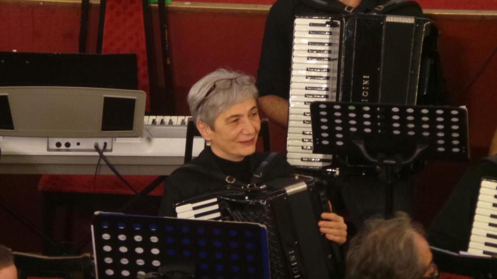an older woman is playing an accordion at Apartments Golubic in Pula