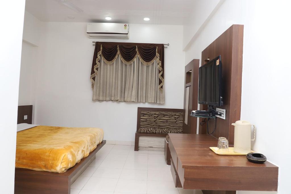 a bedroom with a bed and a table and a tv at The Byke Embassy - Surat in Surat