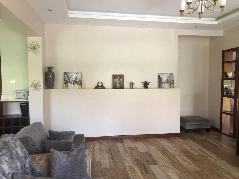 een woonkamer met een bank en een witte muur bij Bridges incorporated limited in Entebbe