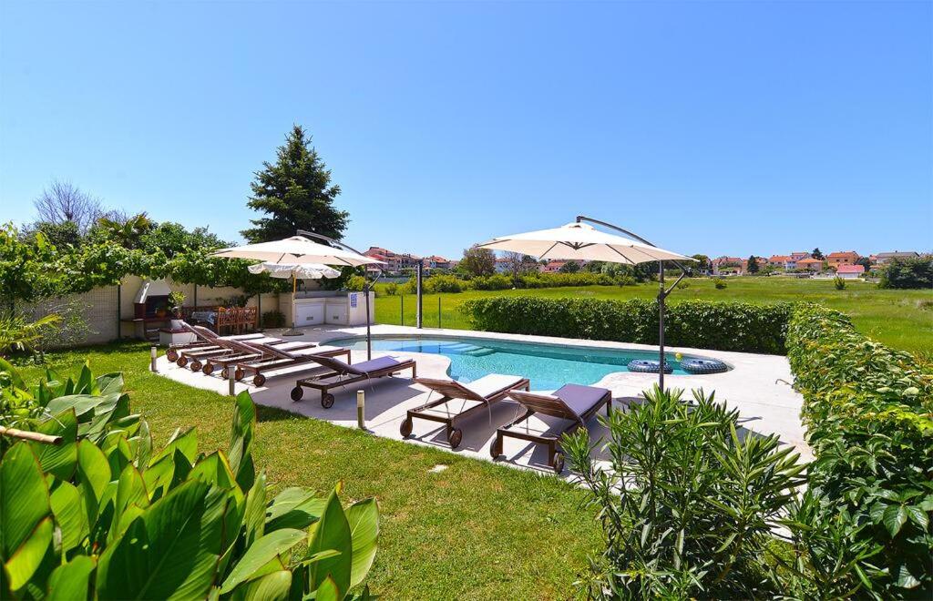 una piscina con tumbonas y sombrillas en Stunning View Apartment with pool, en Valbandon