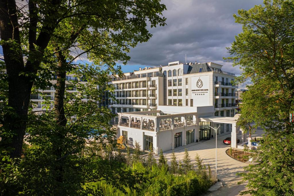 un grande edificio bianco con alberi di fronte di Grand Resort Pavel Banya Medical and SPA EpiCentrum a Pavel Banya