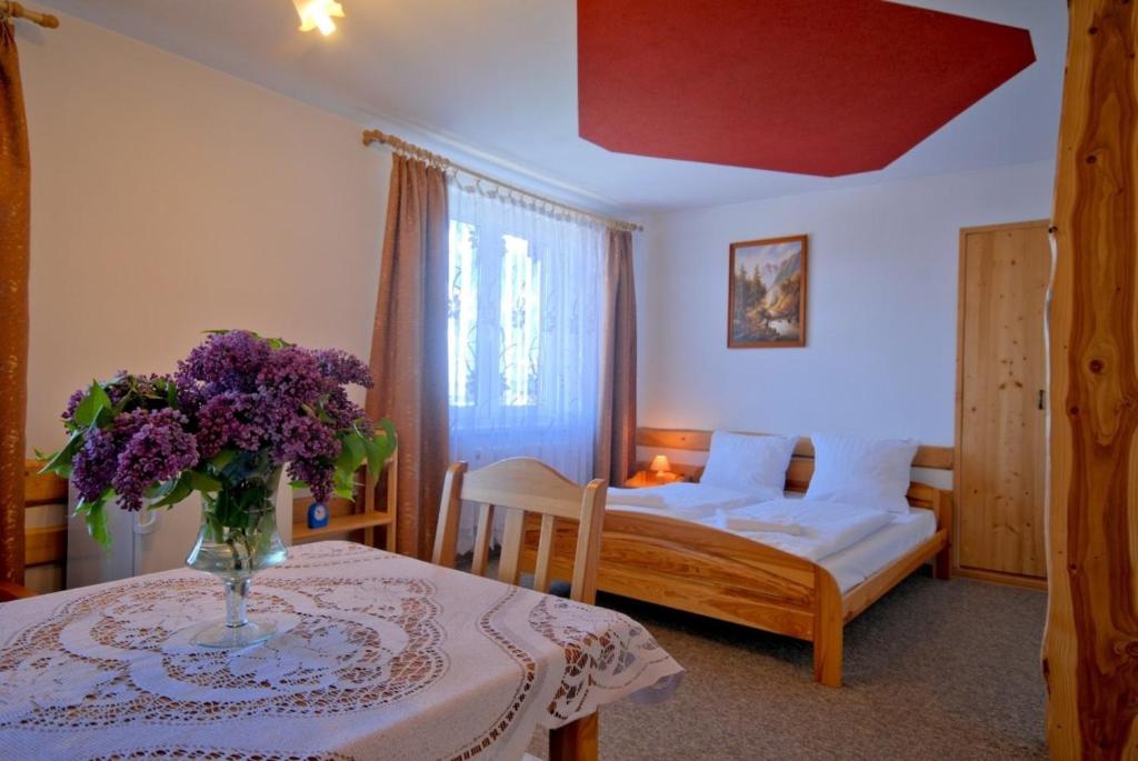 a bedroom with a bed and a table with a vase of flowers at Ośrodek Wczasowy Groń Placówka in Groń