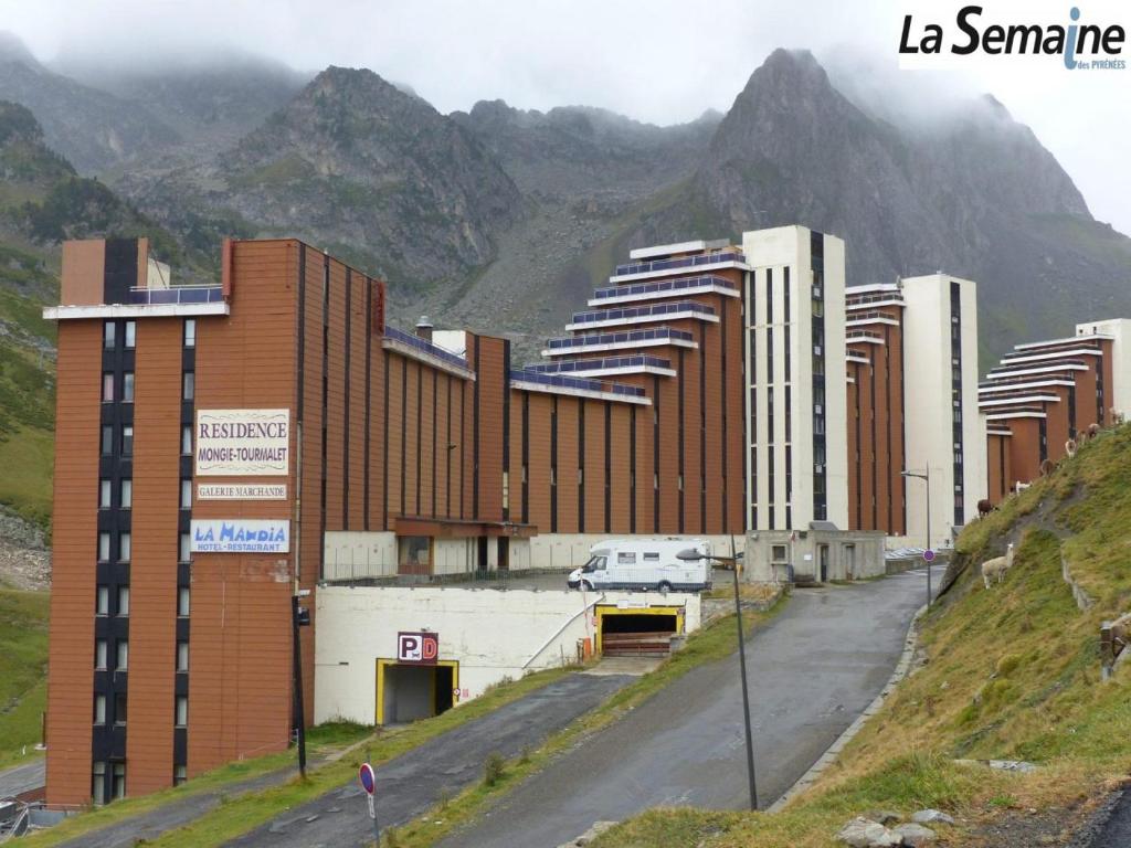 un bâtiment sur une colline avec des montagnes en arrière-plan dans l'établissement Studio Residence Tourmalet-La Mongie, à Bagnères-de-Bigorre