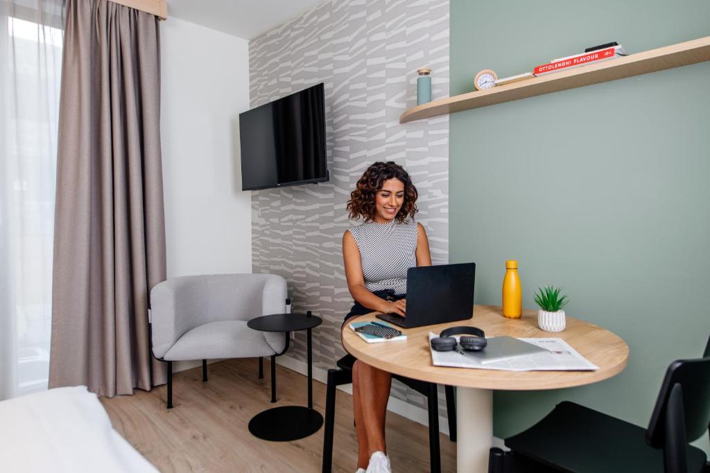 a woman sitting at a table with a laptop at Aparthotel Adagio Muenchen City in Munich