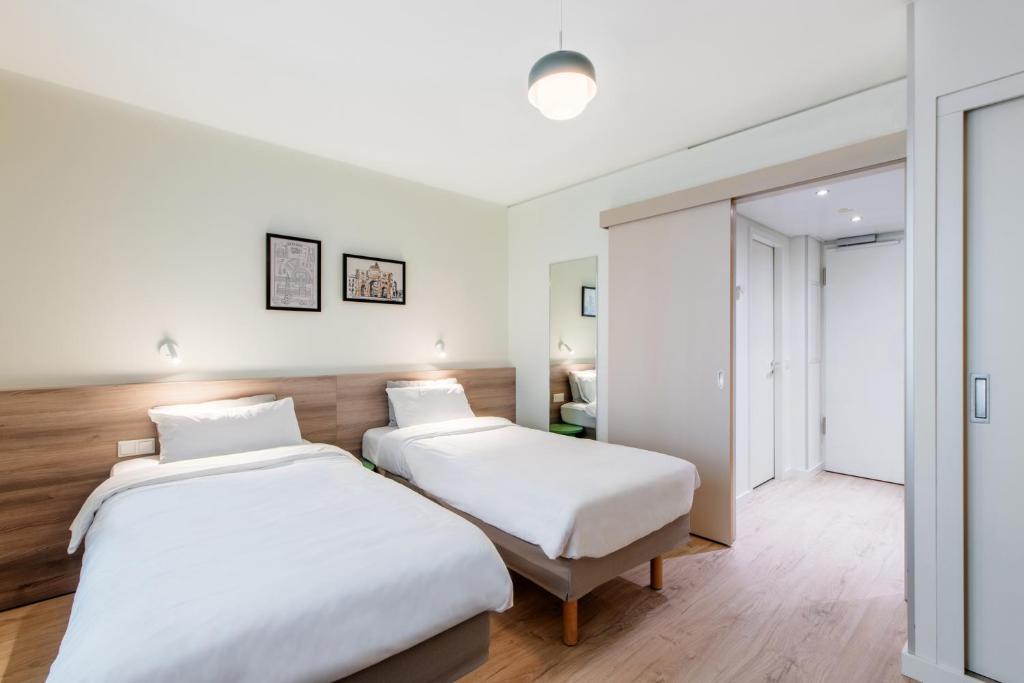 two beds in a room with white walls and wooden floors at Aparthotel Adagio Muenchen City in Munich
