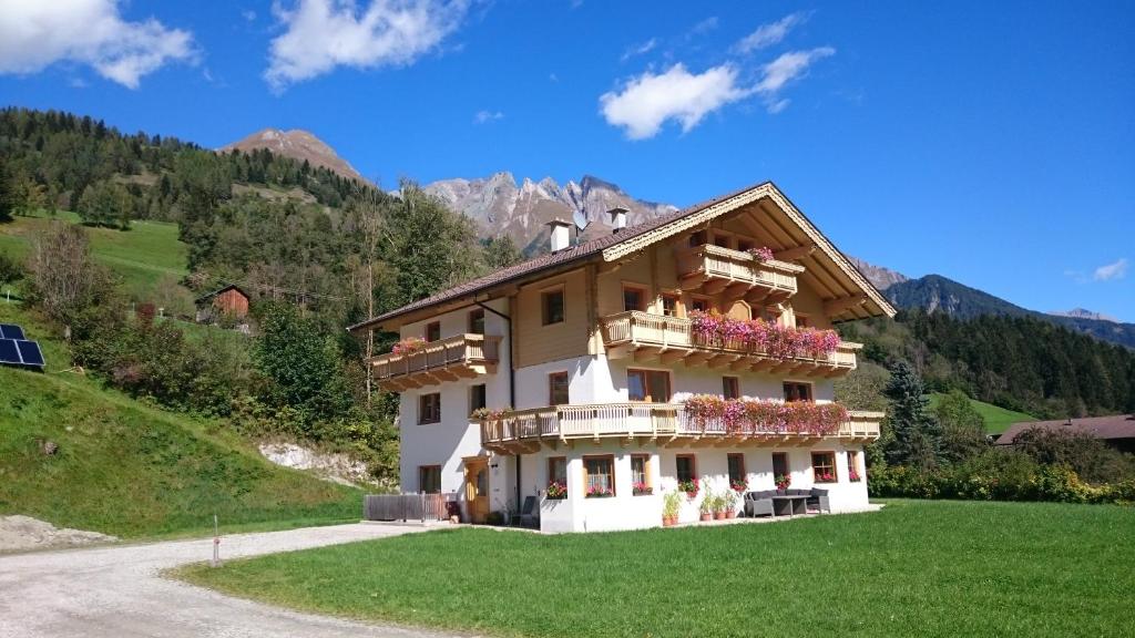 ein Haus auf einem Hügel mit Blumen auf den Balkonen in der Unterkunft Apartment Santnerhof in Virgen