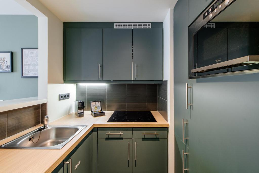 a kitchen with green cabinets and a sink at Aparthotel Adagio Muenchen City in Munich