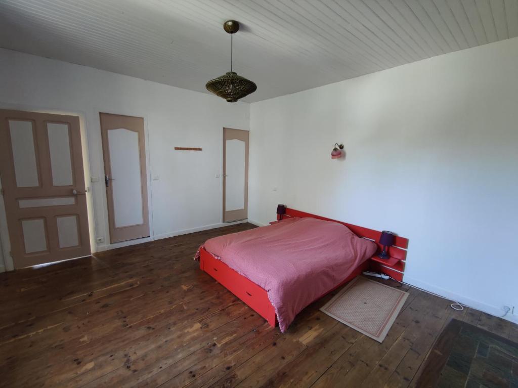 - une chambre avec un lit rouge dans une chambre dotée de parquet dans l'établissement Le Dojo, à Saint-Christophe
